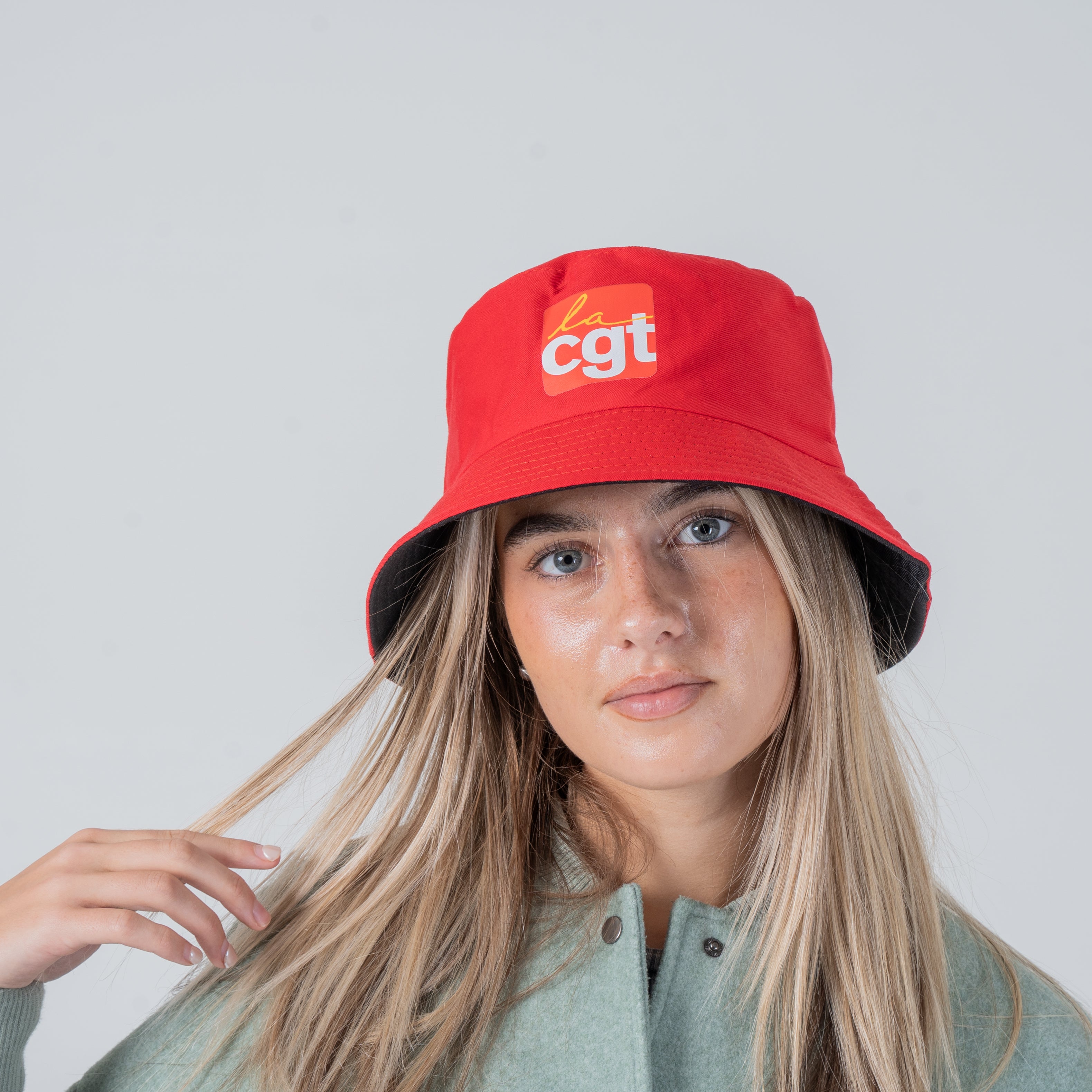 Une femme portant un bob La CGT rouge sur sa tête.